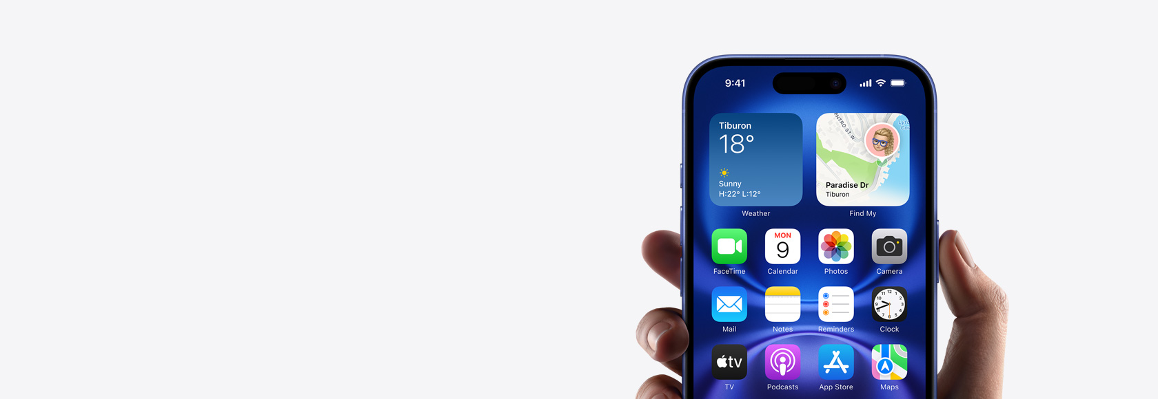 Ruka držící iPhone 16 Pro s fotkou, ikonami a widgety na ploše.