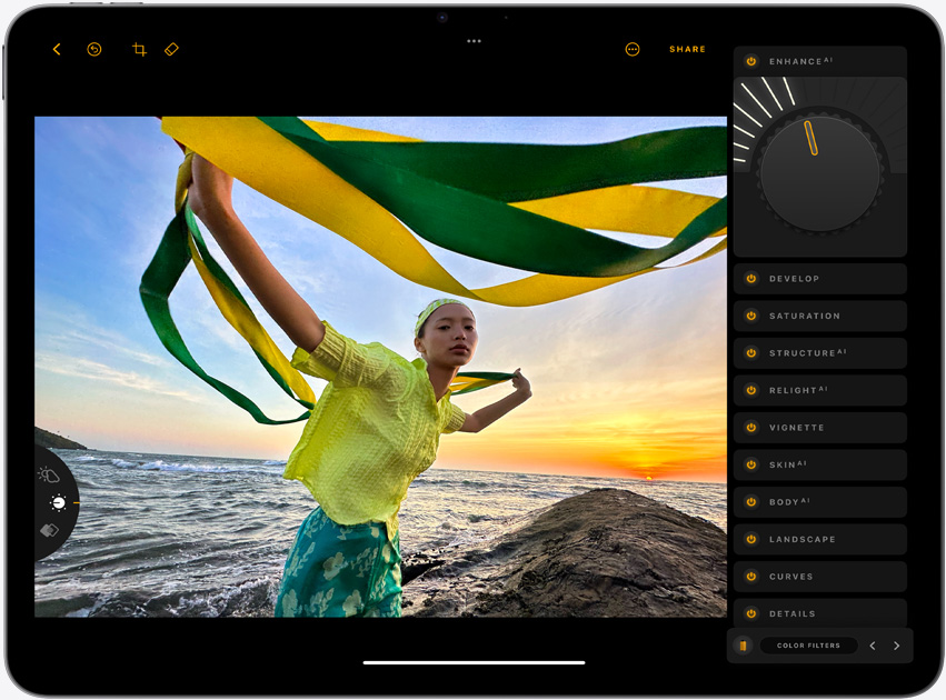iPad Air, orientace na šířku, na obrazovce je fotografie dívky držící žluté a zelené stuhy u oceánu při západu slunce